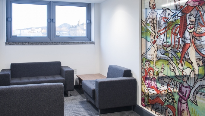 a meeting room with three chairs and a window, plus a large interior window with colourful graphics
